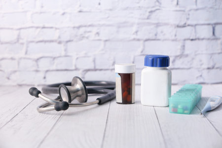stethoscope, medicine container and pills on wooden background