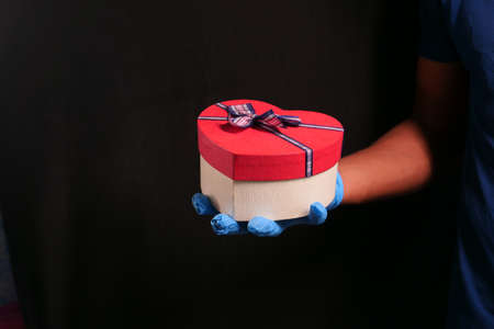 male hand in a blue medical glove gives a gift. isolated in blackの写真素材