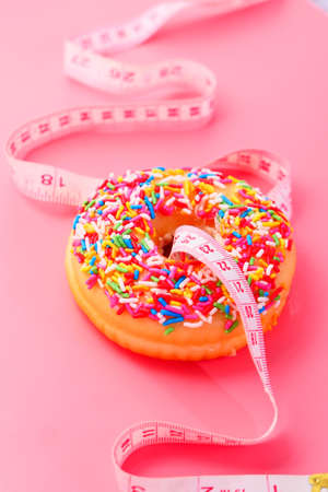 Close up of donuts and measurement tape on pink background.の写真素材