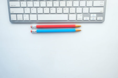 top view of keyboard and color pencils on white background