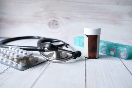stethoscope , pills and container on table