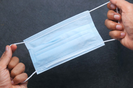 man hand holding surgical face mask, close up