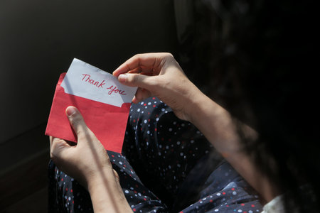 womens hand holding thank you note , top down