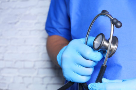 doctor hand in protective gloves holding stethoscope
