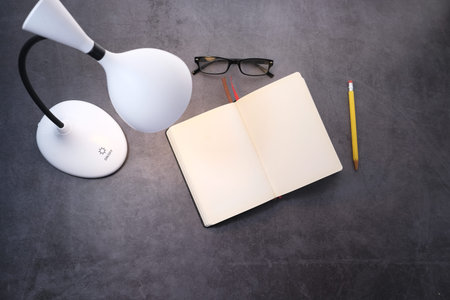 top view of a lamp, diary and pencil on tiles background