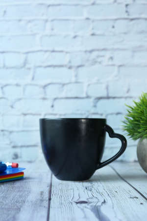 Black mug mockup with with keyboard, notebooks on tableの写真素材