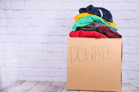 Donation box with donation clothes on a wooden table .