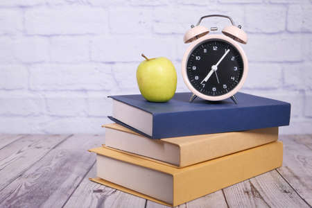 black to school concept with apple and clock on stack of booksの写真素材