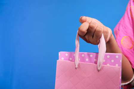 women hand holding shopping bag on blue background .の写真素材