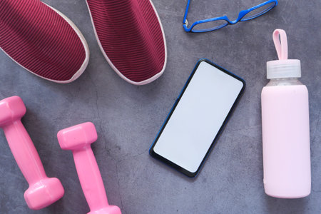 Smart phone with sports equipment on black background
