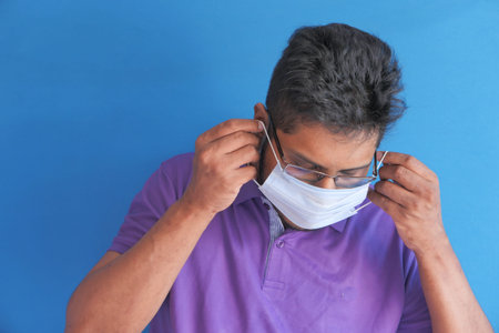 young man wearing protective face mask on blue background