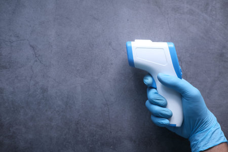 Hand holding infrared thermometer to measuring temperature.