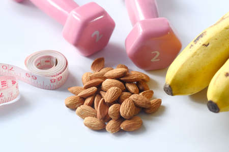 Diet plan with almond nut, dumbbells, banana on table .の写真素材