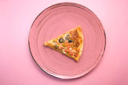 Slice of vegetable pizza on a plate on pink table.の写真素材
