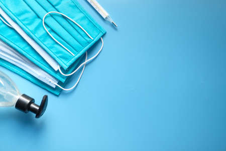 Surgical masks, thermometer and hand sanitizer on blue backgroundの写真素材