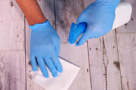 hand in blue rubber gloves holding spray bottle and wiping flat surfaceの写真素材