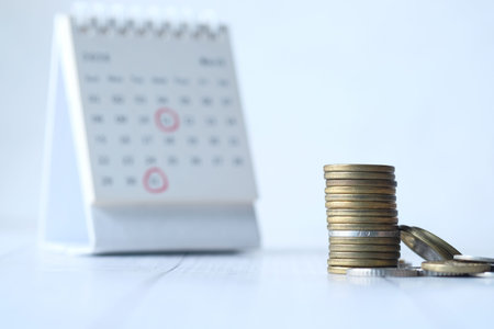 deadline concept with stack of coins and calendar on white background