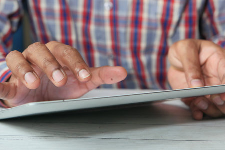 mans hand working on digital tablet on office desk