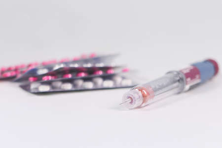 Insulin pen and pills on white background with copy spaceの写真素材