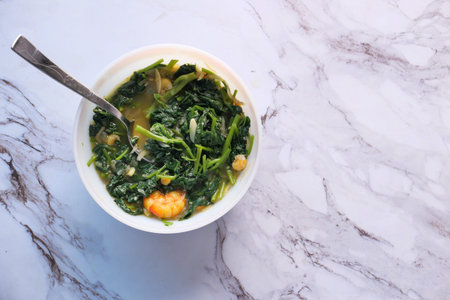 Top view of bowl with cooked spinach on tableの写真素材