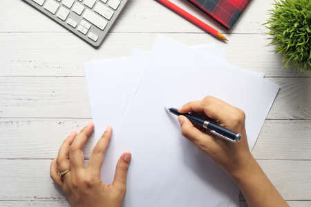 top view of women hand writing on empty paper on tableの写真素材