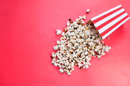 popcorn spilling from a container on red backgroundの写真素材