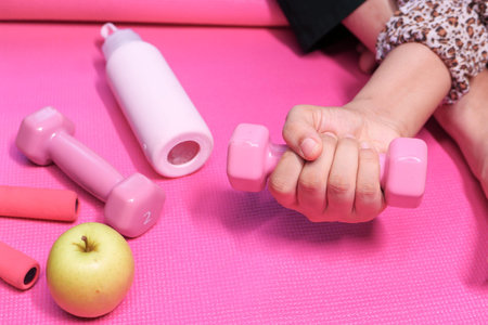 Close up of woman hand holding pink dumbbell.の写真素材