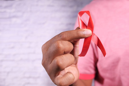 hand holding red HIV ribbon with copy space