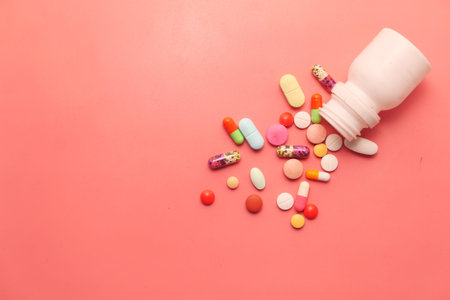 top view of pills and capsule spilling on pink background