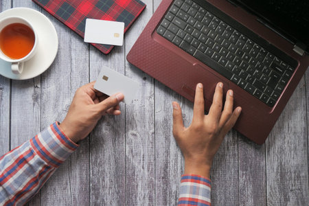 man hands holding credit card and using laptop shopping online