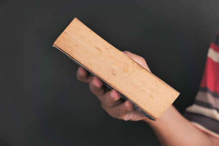 close up of hand holding book on black backgroundの写真素材