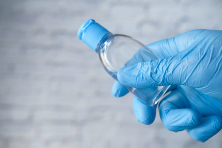 hand in protective gloves holding sanitizer gel