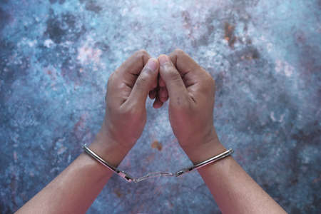 mans hand with handcuff on black background.の写真素材