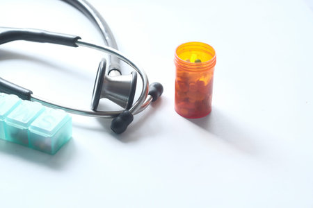stethoscope and pills container on white background