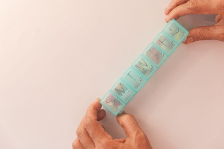 Top view of senior hands taking medicine from a pill box