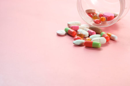 close up of colorful pills spilling on white background