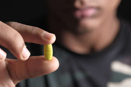 close up of man hand holding pills isolated on blackの写真素材