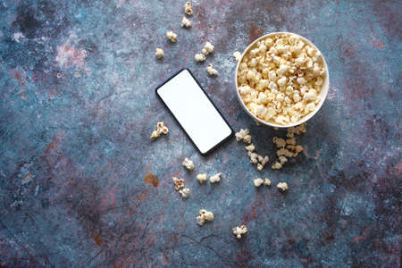 top view of smart phone and popcorn on tableの写真素材
