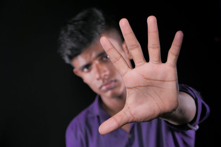 young man show stop sigh isolated in black