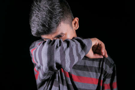Young ill man covering her nose and mouth with arm.の写真素材
