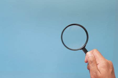 hand holding magnifying glass on color backgroundの写真素材