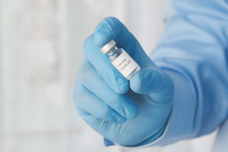 doctor hand in gloves holding coronavirus vaccine, close up