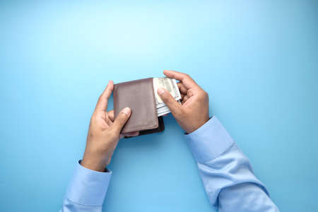 man hand taking cash out from wallet on blue backgroundの写真素材