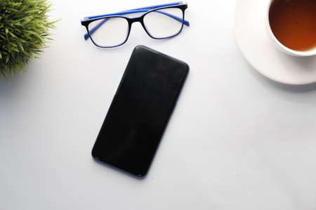 top view of smart phone, eyeglass and tea on tableの写真素材
