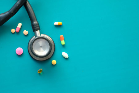 colorful pills and stethoscope on green background