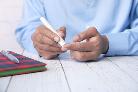 young mans hand measure glucose level at home