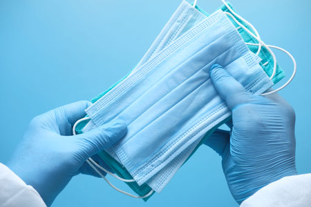 doctor hand in medical glove holding protective surgical face mask, close up