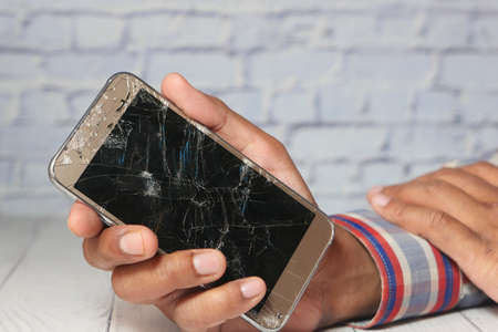 Close up of man hand holding broken smart phone.の写真素材