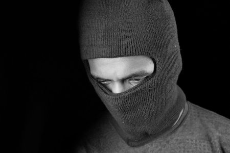 Thief in a mask on black background close up,