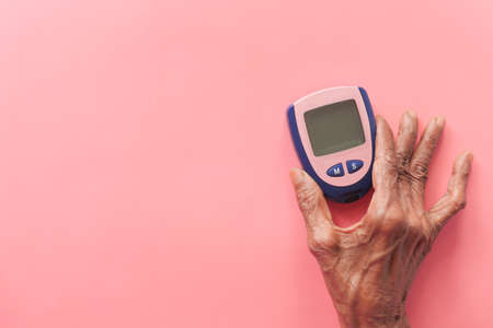senior women holding diabetic measurement tools on pinkの写真素材